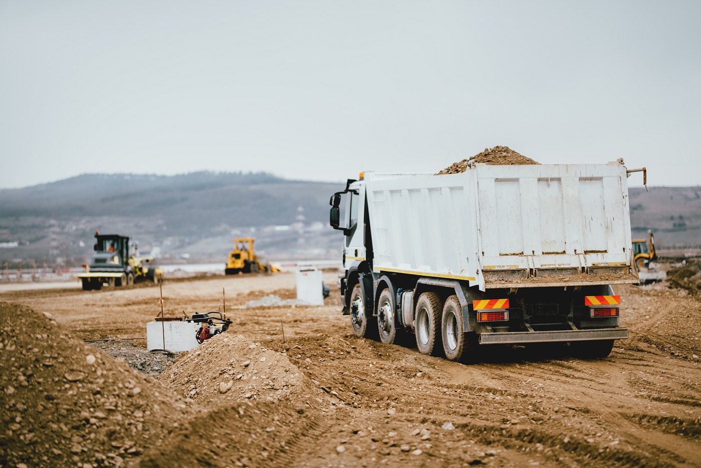 Industrial dumper trucks working on highway construction site, loading and unloading earth. heavy duty machinery activity